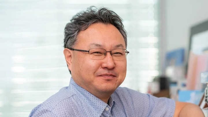 Shuhei Yoshida posing in a home. He's wearing a blue button-up shirt.